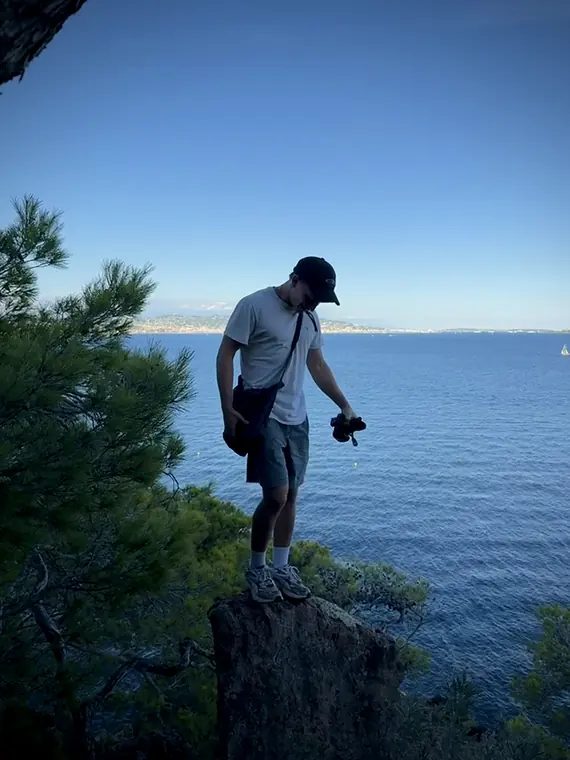 Clemens mit Kamera auf einem Felsen über dem Meer