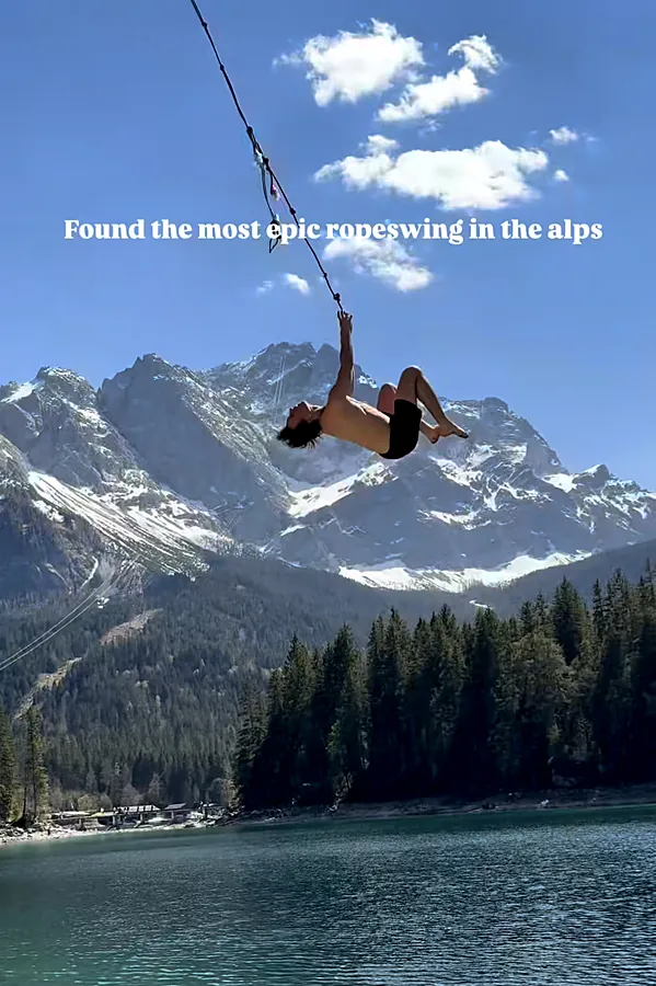 Salto am Rope Swing über einem Bergsee vor verschneiten Gipfeln