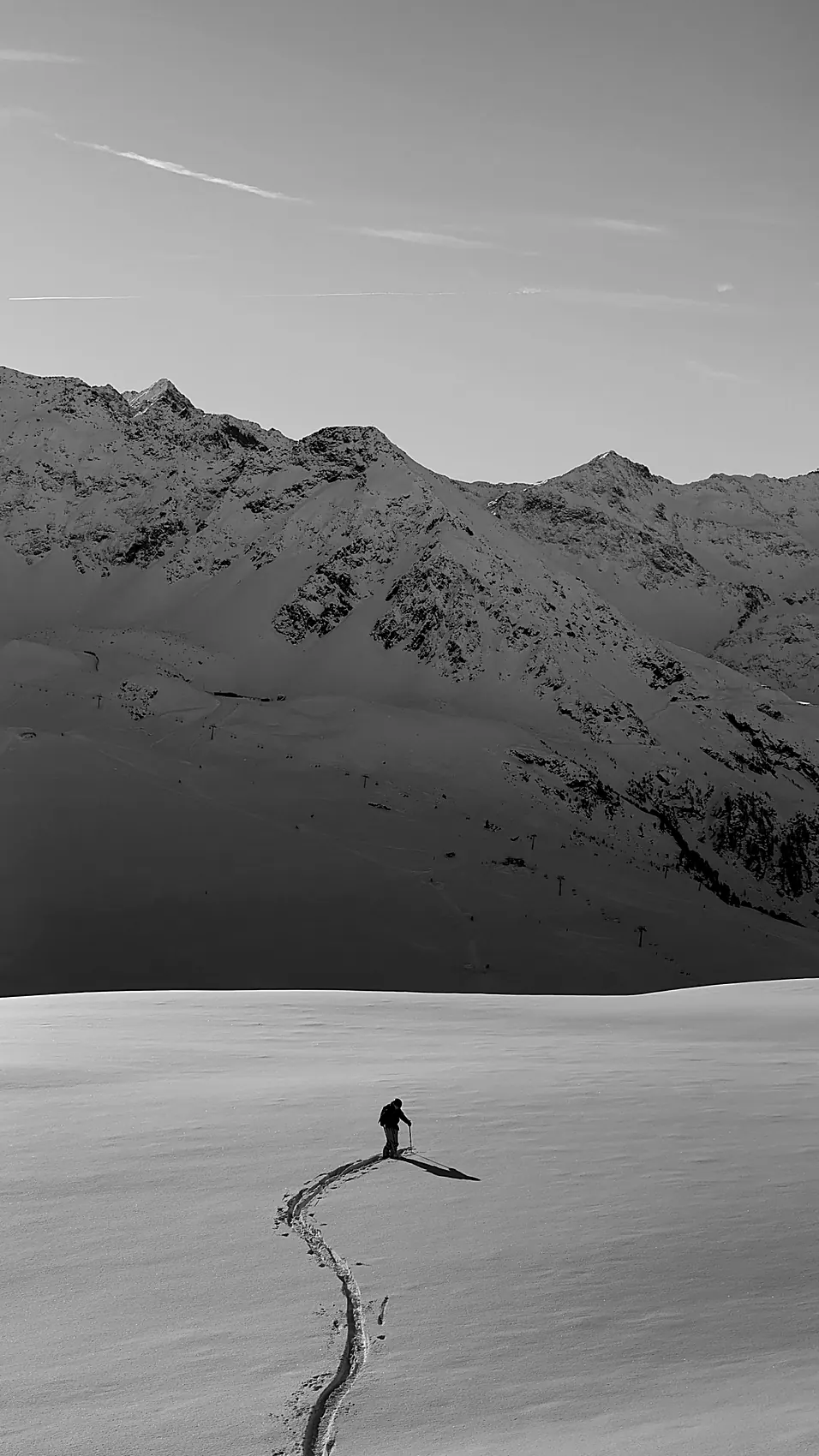 Schwarz-weiß: Skitourengeher zieht eine Spur durch den Tiefschnee