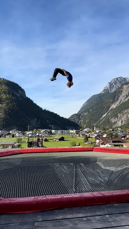 Backflip auf einem Freestyle-Trampolin vor einem Bergpanorama